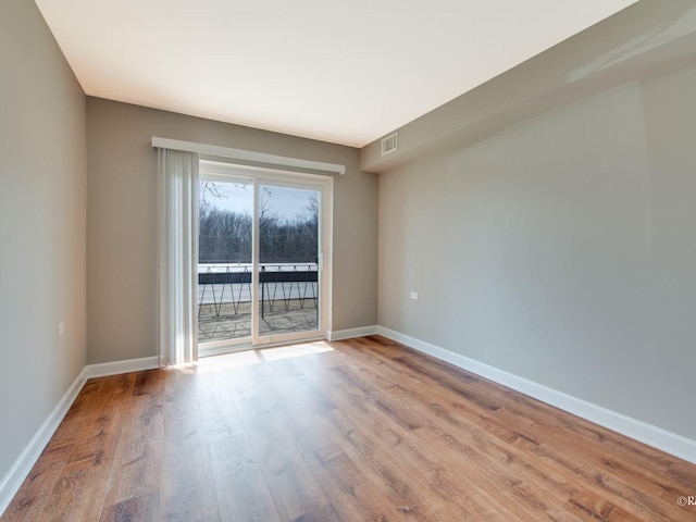 spare room featuring visible vents, baseboards, and wood finished floors