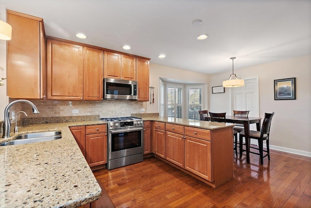 kitchen with a sink, decorative backsplash, appliances with stainless steel finishes, and a peninsula