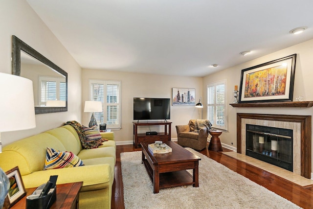 living area with a tiled fireplace, baseboards, and wood finished floors