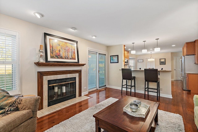 living area with baseboards, dark wood-style flooring, and a tile fireplace