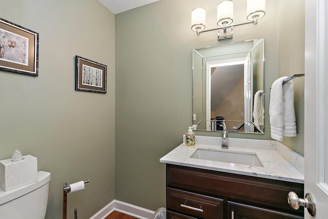 bathroom featuring toilet, vanity, and baseboards