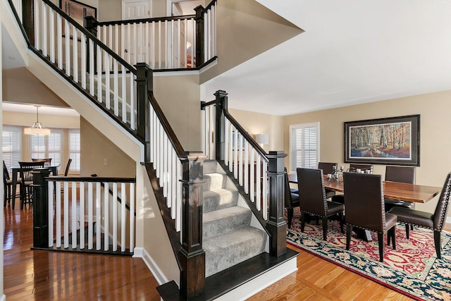 stairs featuring baseboards, wood finished floors, and a towering ceiling