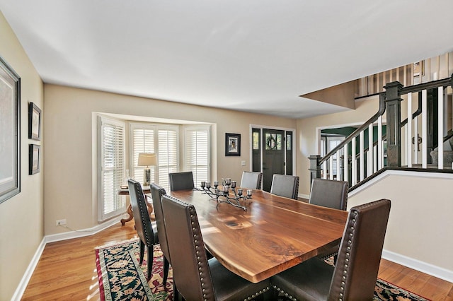 dining space featuring stairway, light wood-style flooring, and baseboards