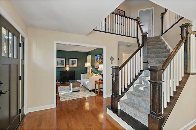 entrance foyer with baseboards, wood finished floors, and stairs