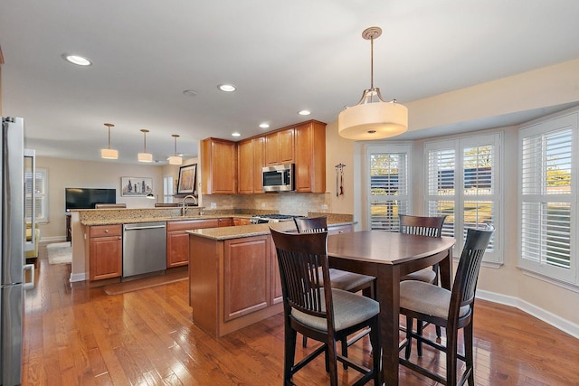 kitchen with tasteful backsplash, appliances with stainless steel finishes, a peninsula, plenty of natural light, and a sink