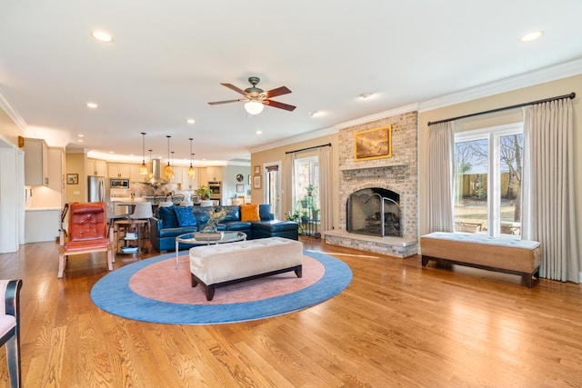 living room featuring a fireplace, light wood-style flooring, and crown molding