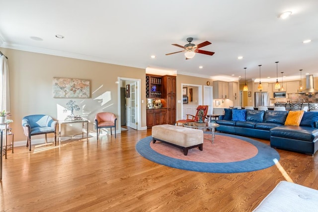 living room with baseboards, recessed lighting, ornamental molding, ceiling fan, and light wood-style floors