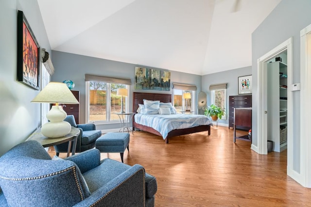 bedroom featuring high vaulted ceiling, baseboards, and wood finished floors