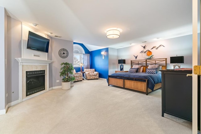 carpeted bedroom with vaulted ceiling, baseboards, and a tile fireplace