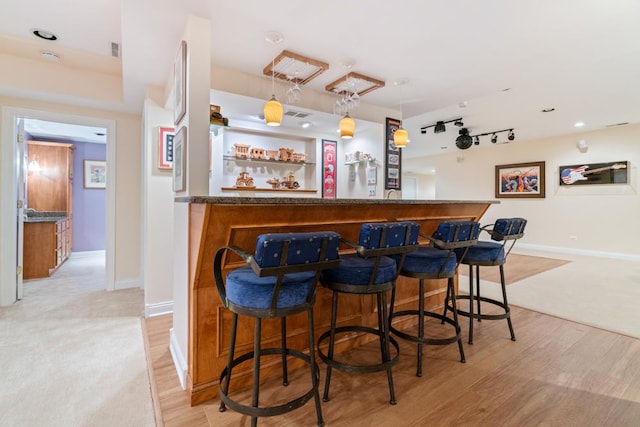 bar featuring track lighting, baseboards, light wood-style floors, and indoor bar