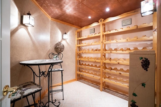 wine area with light tile patterned floors, an ornate ceiling, baseboards, and ornamental molding