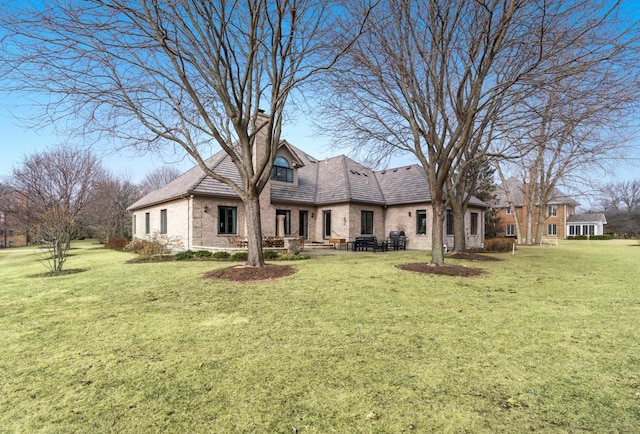 back of property featuring brick siding, a lawn, and a chimney