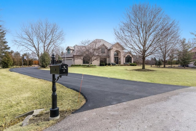 view of front of property with a front yard, stone siding, and driveway