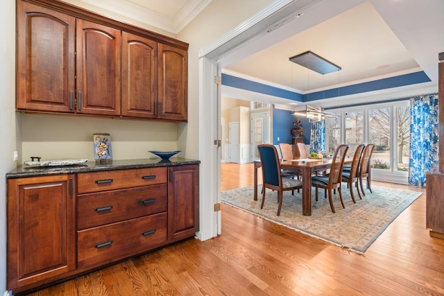 dining room featuring wood finished floors, a tray ceiling, and ornamental molding