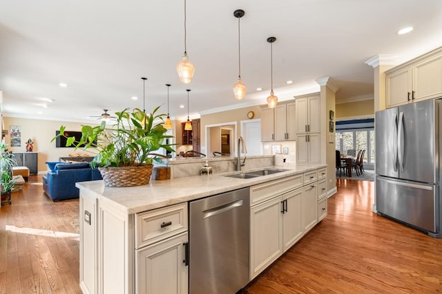 kitchen with light wood-style flooring, a sink, stainless steel appliances, crown molding, and open floor plan