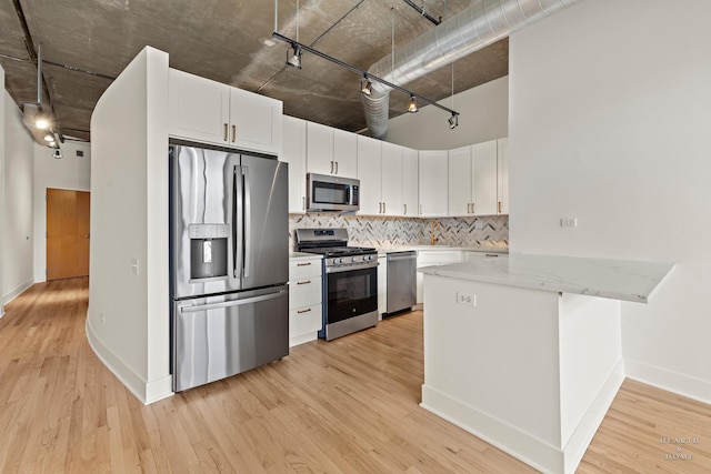 kitchen featuring stainless steel appliances, white cabinetry, decorative backsplash, and light wood finished floors