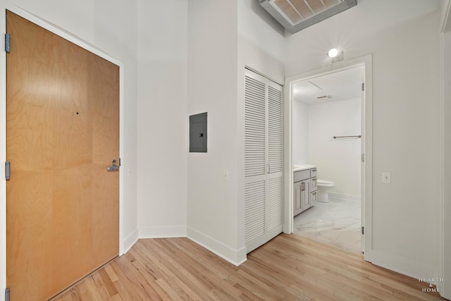 hallway with electric panel, baseboards, and light wood-style floors