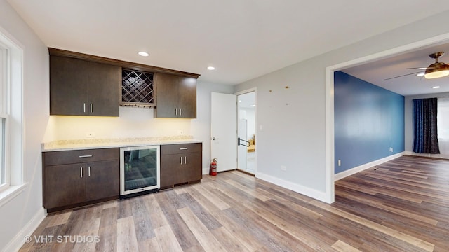 bar featuring beverage cooler, light wood-style flooring, and a bar