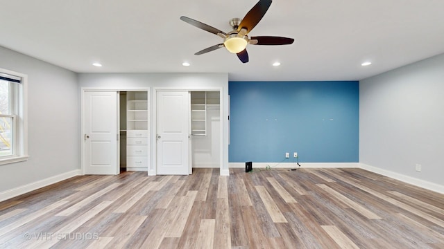 unfurnished bedroom with two closets, a ceiling fan, wood finished floors, recessed lighting, and baseboards