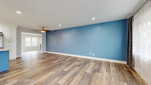 unfurnished living room with recessed lighting, light wood-type flooring, and baseboards