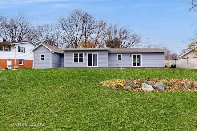 rear view of house featuring a lawn and fence