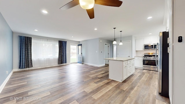 kitchen featuring light wood finished floors, stainless steel appliances, white cabinetry, open floor plan, and a center island