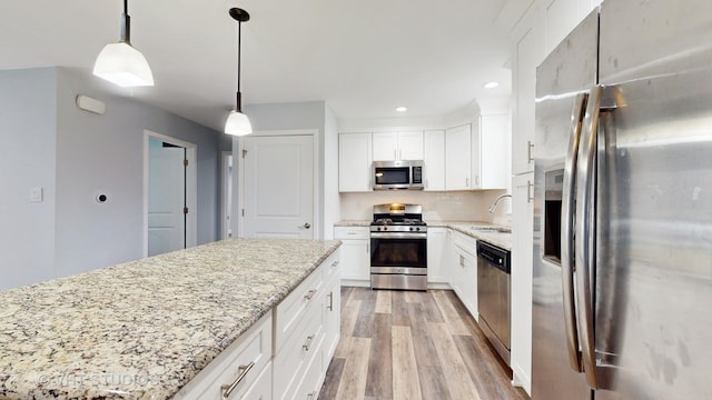 kitchen featuring a sink, light wood-style flooring, light stone countertops, and stainless steel appliances