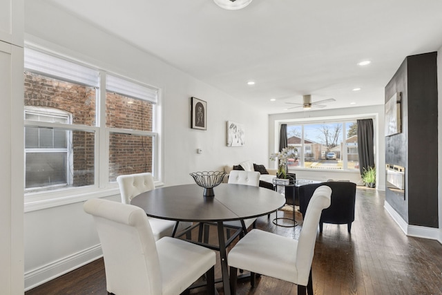 dining room featuring dark wood-type flooring, baseboards, recessed lighting, a fireplace, and a ceiling fan