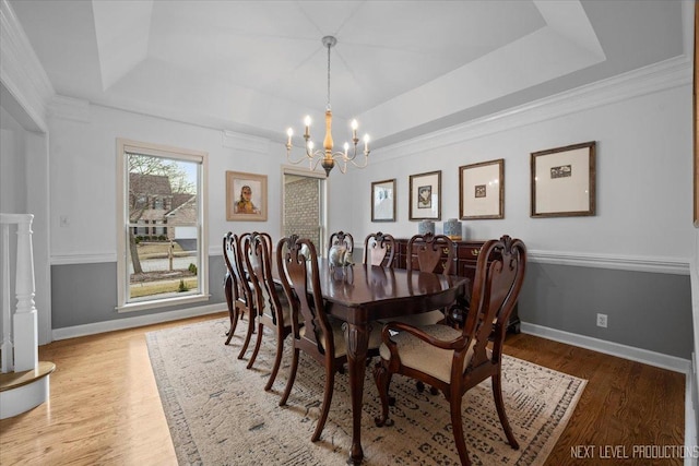 dining space featuring a chandelier, a tray ceiling, and wood finished floors