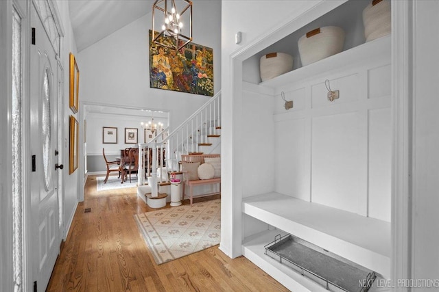 mudroom featuring light wood-style floors, a notable chandelier, and high vaulted ceiling