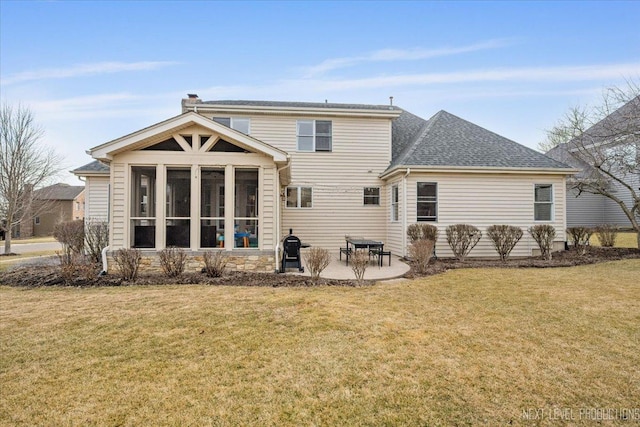 back of property featuring a lawn, a patio, roof with shingles, a sunroom, and a chimney