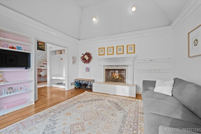 living area featuring crown molding, stairs, a premium fireplace, wood finished floors, and high vaulted ceiling