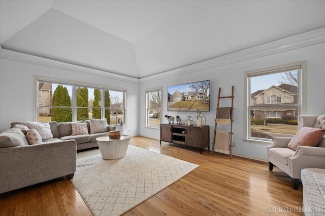 living room featuring vaulted ceiling, light wood-style floors, baseboards, and a healthy amount of sunlight