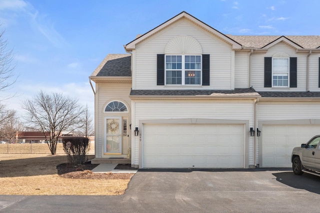 townhome / multi-family property with a garage, driveway, and a shingled roof