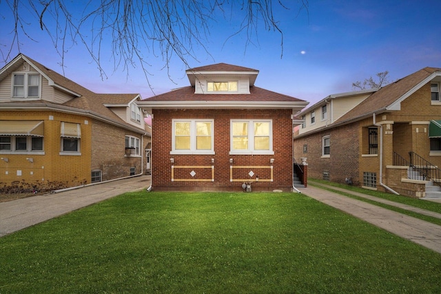 view of front of house featuring a yard, brick siding, and a shingled roof