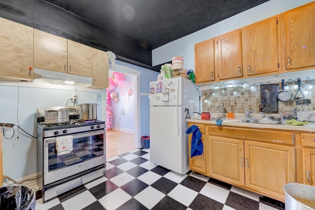 kitchen with tile patterned floors, a sink, freestanding refrigerator, light countertops, and stainless steel gas range