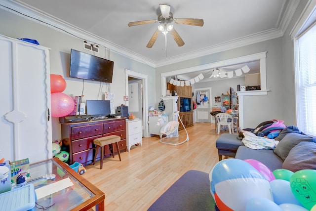 living room with crown molding, a ceiling fan, and light wood-type flooring