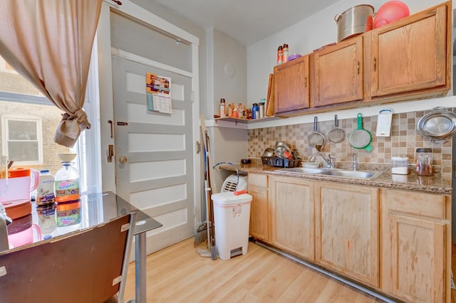 kitchen with light stone countertops, light wood finished floors, open shelves, a sink, and decorative backsplash