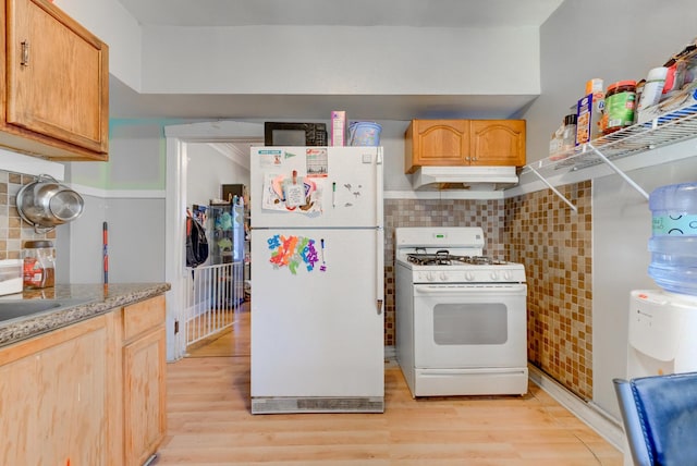 kitchen with light wood-type flooring, under cabinet range hood, backsplash, white appliances, and light countertops