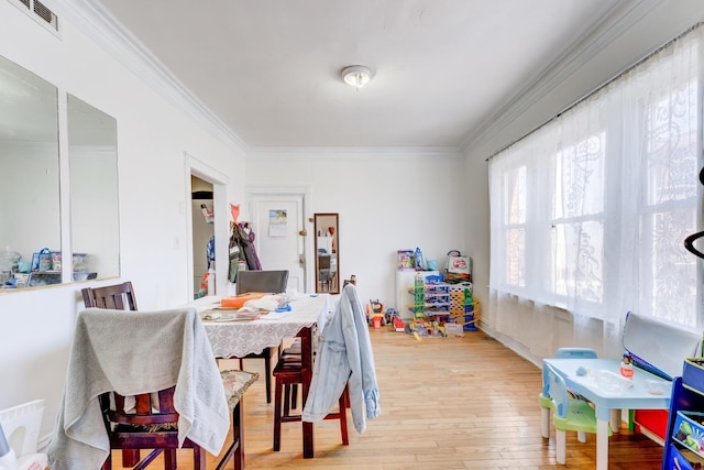 dining room featuring visible vents, light wood-style floors, and ornamental molding