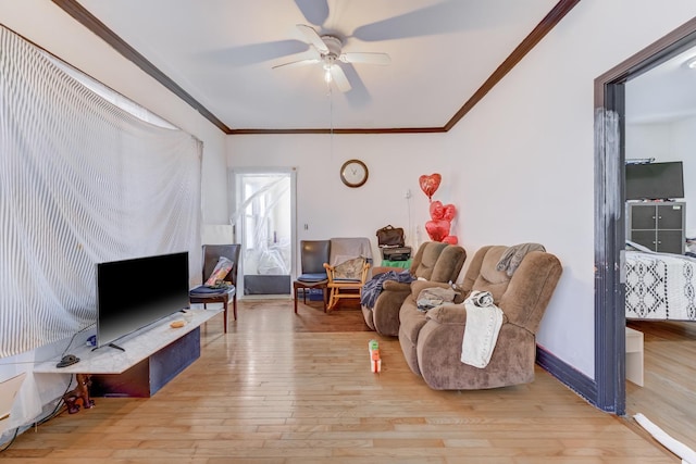 living area with baseboards, crown molding, a ceiling fan, and wood-type flooring