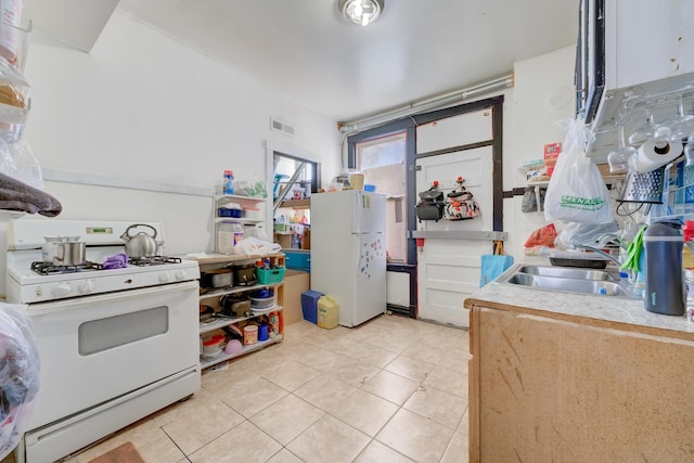 kitchen featuring visible vents, light countertops, light tile patterned floors, white appliances, and a sink