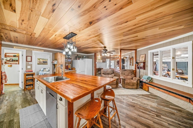 kitchen with wood finished floors, wooden counters, freestanding refrigerator, a sink, and stainless steel dishwasher