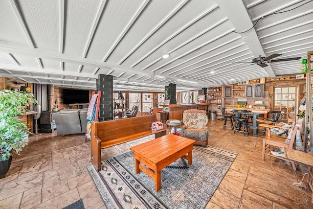 living area featuring stone tile floors, a ceiling fan, and vaulted ceiling