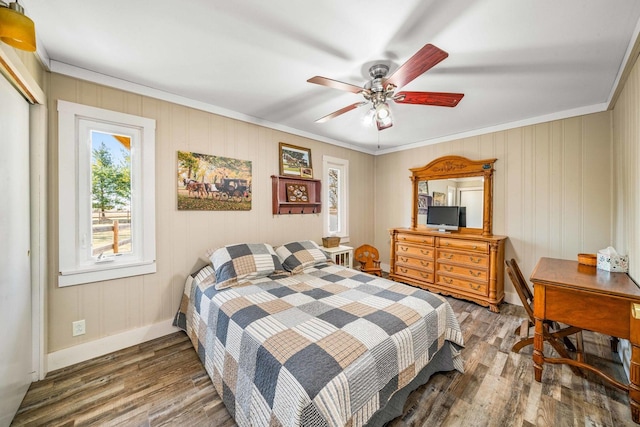 bedroom featuring ceiling fan, baseboards, ornamental molding, wood finished floors, and a closet