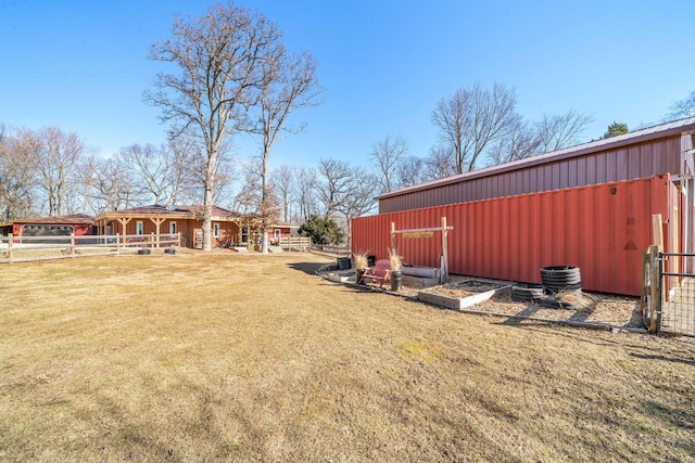 view of yard with an outbuilding, fence, and a pole building