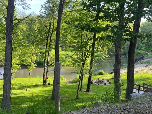 surrounding community featuring a yard, a water view, and an outdoor fire pit