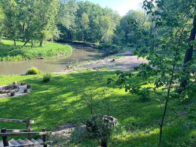 view of yard featuring a fire pit, a water view, and a forest view