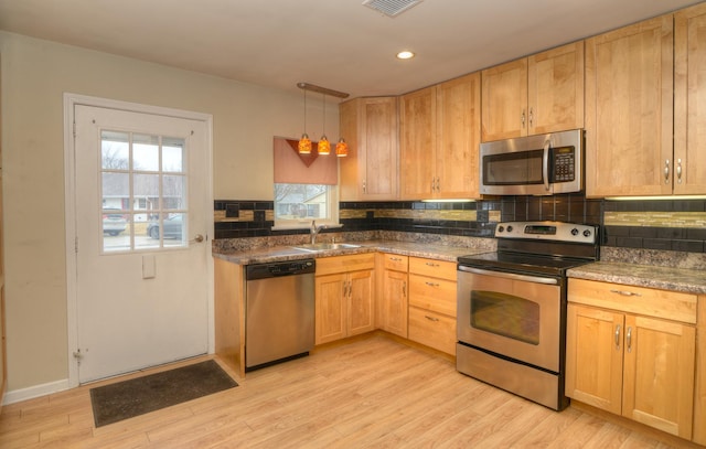 kitchen featuring backsplash, stainless steel appliances, light wood-type flooring, and a sink