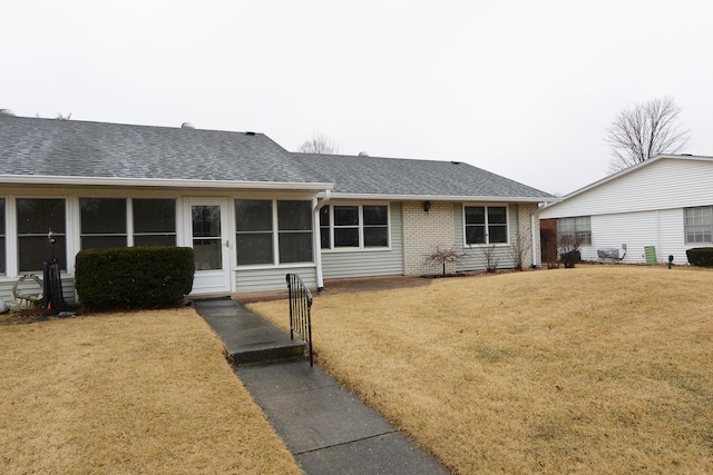 ranch-style home featuring a front yard, brick siding, and a shingled roof